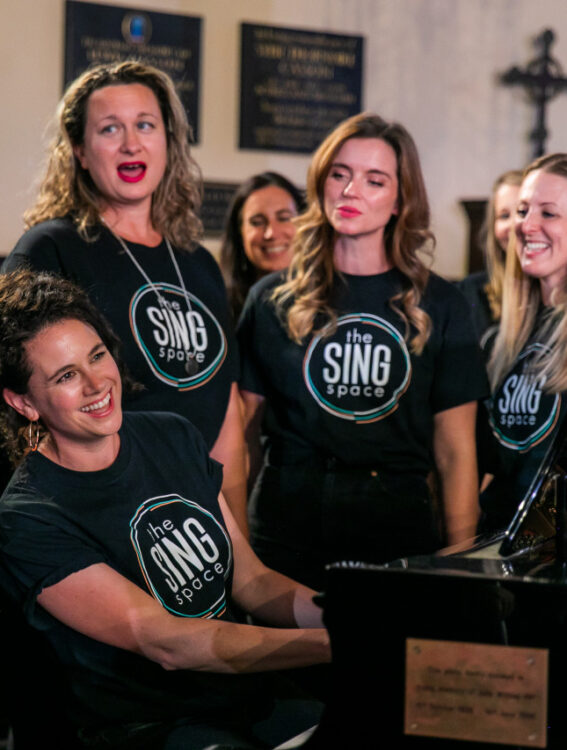 choir singing around a piano